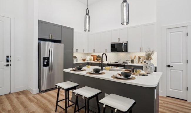 Stainless steel appliances and an island inside the model apartment kitchen at Copper Bishop Arts